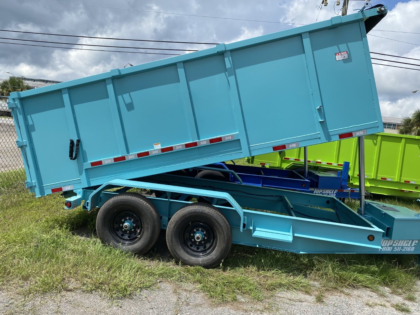 Side view of aqua dump trailer with bed raised